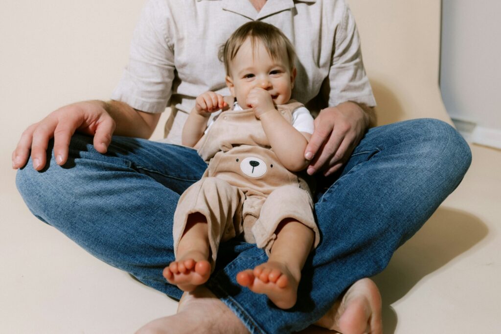 パパのあぐらの上に座って微笑んでいる2歳くらいの男の子