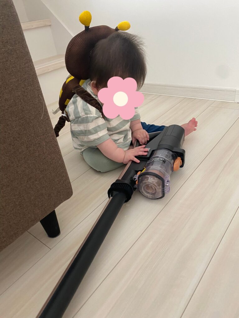 転倒防止リュックを背負って掃除機にいたずらしている長男の写真