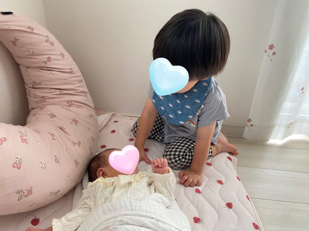 わが家の2歳長男が寝ている0歳長女を見ている写真