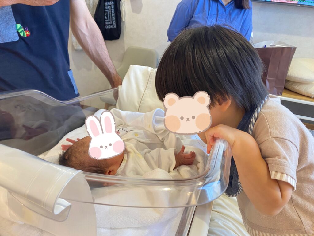 妹と初対面の長男。コットをのぞきこんでいる写真